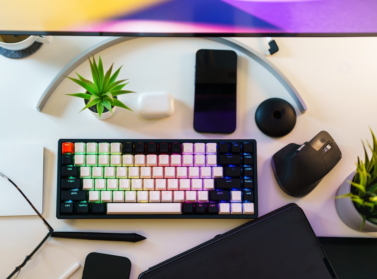 Mesa de escritório com teclado, mouse e celular, vistos de cima